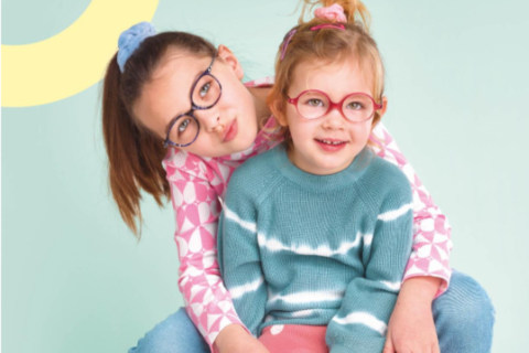 lunettes pour enfants deux jeunes filles portant des lunettes. elles sont assises et sourient. c'est une photo produite par OptiKid, opticien Nanterre ville