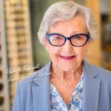 Une cliente très satisfaite de ses lunettes, porte des lunettes bleues à pois blanc de la marque L.A.Eyeworks, achetées chez TOUT'Optique, avec une monture conseillée par nos opticiens visagistes